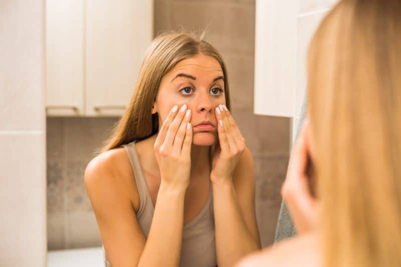 Woman looking at her eyes in the mirror