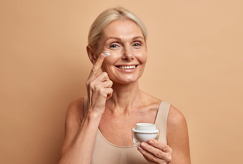 Woman applying cream to her face