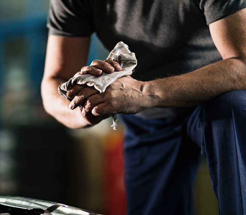 Mid body shot of a male mechanic rubbing oil off of his hands