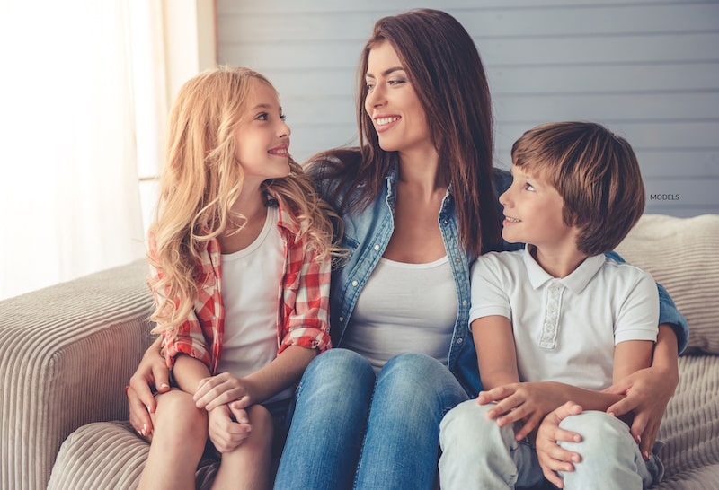 Women sitting on a couch with her two kids.