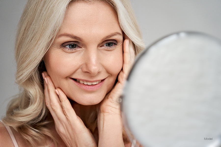 Beautiful older woman smiling at her reflection in a mirror