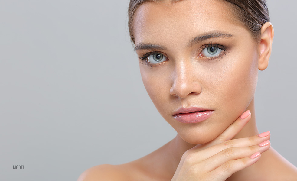 close up of model's face with one hand resting under her chin